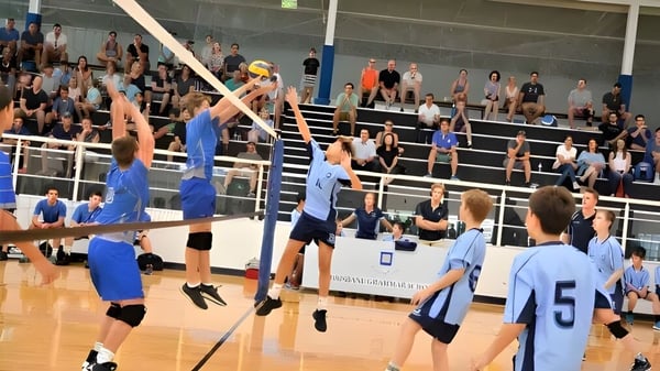 Eine Gruppe von Volleyballspielern der Brisbane Grammar School spielt ein Match auf dem Spielfeld vor Zuschauern.