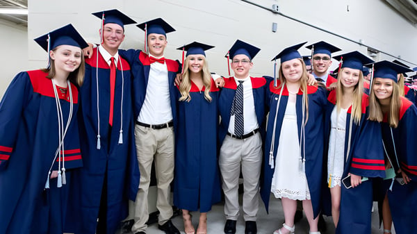 Eine Gruppe von Absolventen der Brisbane State High School feiert in ihren roten und blauen Talaren im Flur ihren Abschluss.