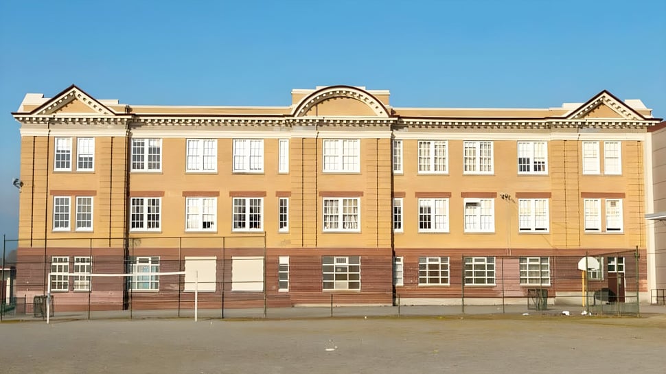 Das mehrstöckige Backsteingebäude mit verzierten architektonischen Details der Britannia Secondary School ist vor klarem blauem Himmel zu sehen.