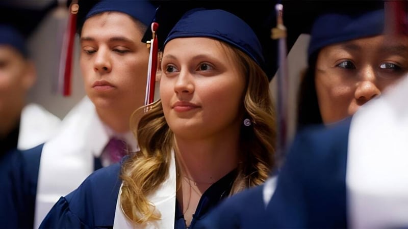 Eine Gruppe von Absolventinnen und Absolventen in blauen Talaren bei der Abschlussfeier der British International School Houston.