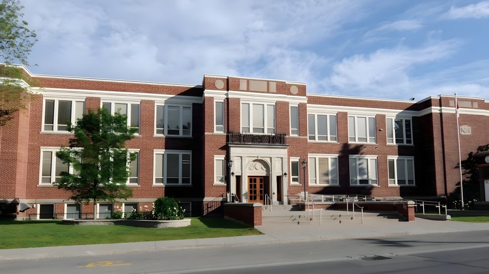 Das mehrstöckige Backsteingebäude mit großem Eingang und Säulen steht auf dem Campus des Brockville Collegiate Institute.