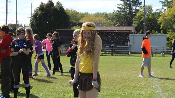 Eine Gruppe Schüler auf einer Wiese mit umgebenden Bäumen vor einem Gebäude auf dem Campus der Brockville Collegiate Institute.