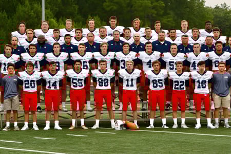 Eine Gruppe von Fußballspielern steht auf dem Fußballfeld der Brook Hill School vor Bäumen.