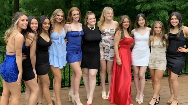 Eine Gruppe junger Frauen in farbenfrohen Kleidern posiert gemeinsam im Grünen auf dem Gelände von Brooke House College.