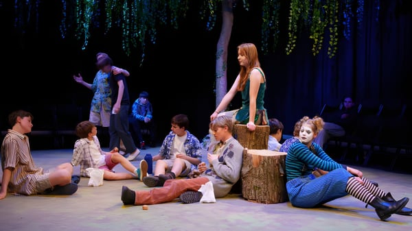 Eine Gruppe von Schülern und Erwachsenen des Brooke House College versammelt sich um einen Baumstumpf in einem schattigen Wald.