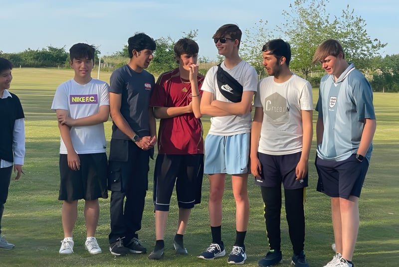 Eine Gruppe Schüler der Brookes UK steht gemeinsam auf einer Wiese mit Bäumen im Hintergrund.