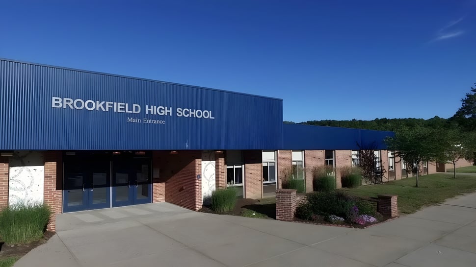 Das große blaue Gebäude der Brookfield High School ist von einem gepflasterten Gehweg und einer gepflegten Landschaft umgeben.