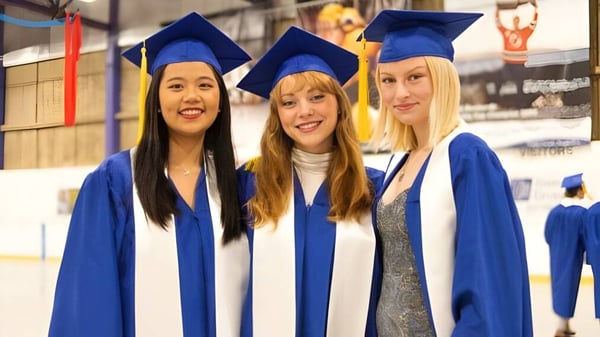 Drei Schülerinnen in blauen Abschlussgewändern feiern ihren Erfolg an der Brooks Secondary School.