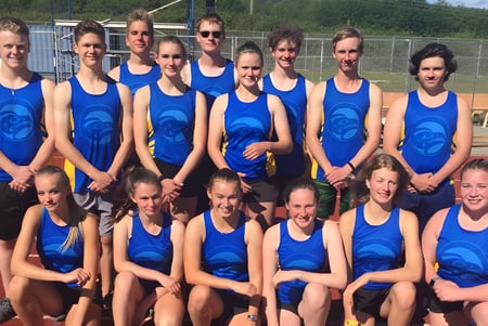 Eine Gruppe junger Schülerinnen in blauer Uniform steht auf dem Sportplatz der Brooks Secondary School.