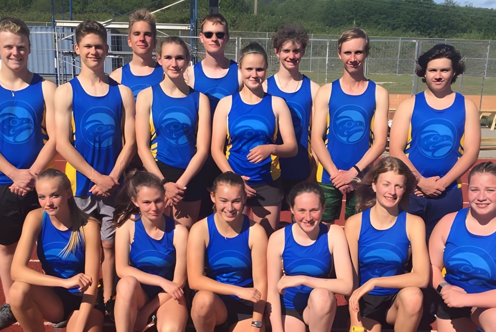 Eine Gruppe junger Schülerinnen in blauer Uniform steht auf dem Sportplatz der Brooks Secondary School.