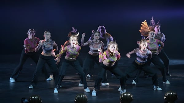 Eine Gruppe von Tänzerinnen und Tänzern führt auf der Bühne der Bryanston School ein farbenfrohes Tanzstück auf.