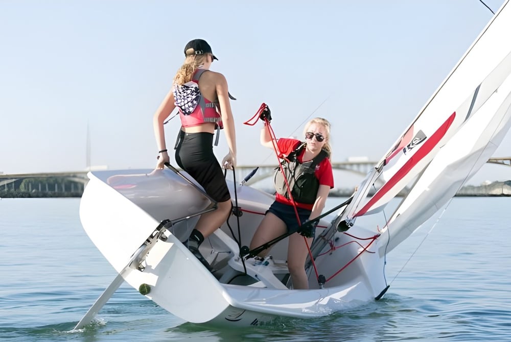 Zwei Frauen in Badebekleidung stehen auf einem kleinen weißen Boot auf dem Wasser in der Nähe von Buffalo Seminary.