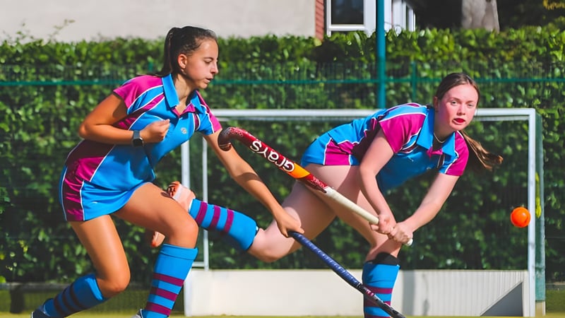 Zwei Schülerinnen der Burgess Hill Girls spielen ein Feldhockeyspiel auf einem Spielfeld mit Tor.