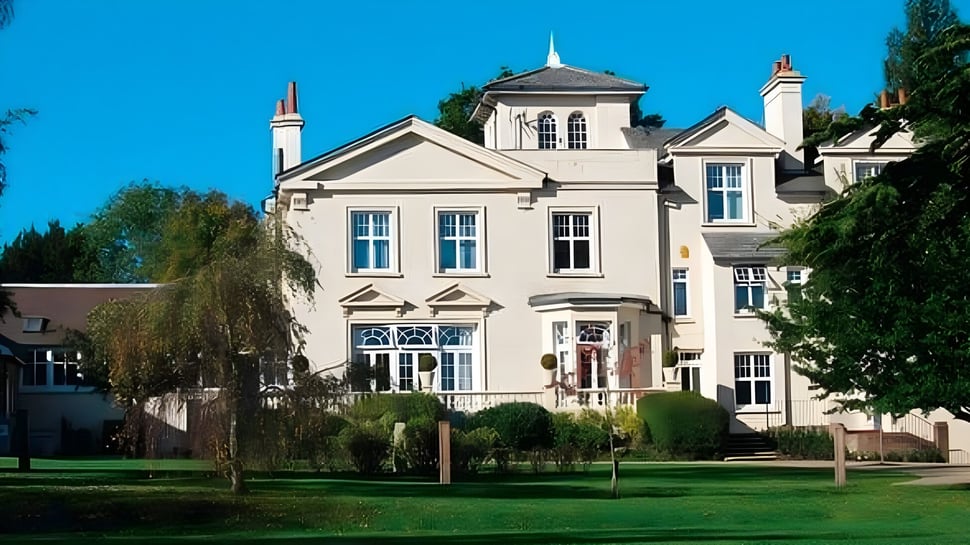 Das mehrstöckige Schulgebäude der Burgess Hill Girls ist von Grünflächen und einem gepflegten Rasen umgeben.