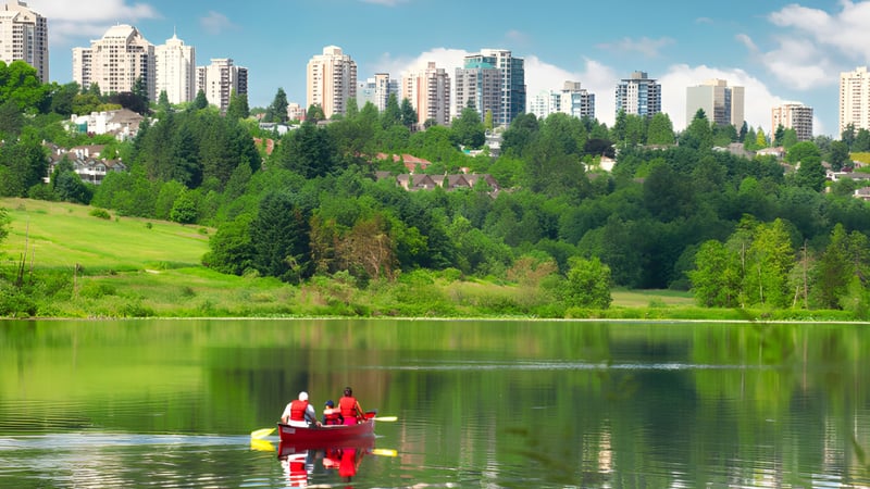 Zwei Personen paddeln in einem Kajak auf einem See vor der Kulisse moderner Gebäude auf dem Gelände der Burnaby South School.