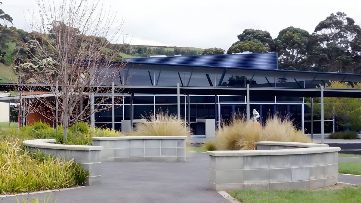 Das moderne Glas- und Stahlgebäude mit geneigtem Dach auf dem Campus der Burnie High School ist von gepflegten Gärten umgeben.
