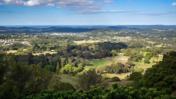 Grüne Landschaft mit Hügeln, Wäldern und einer kleinen Stadt im Hintergrund, nahe der Burnside State High School.