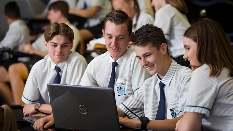 Eine Gruppe Schüler in Schuluniformen arbeitet gemeinsam an einem Laptop am Burpengary State Secondary College.