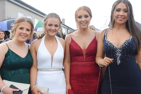 Vier Schülerinnen der Bush Post Primary School posieren gemeinsam in formeller Kleidung im Freien.