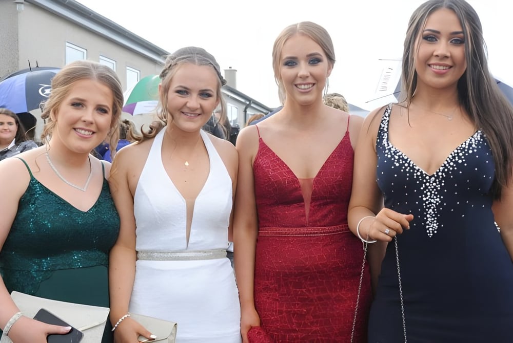 Vier Schülerinnen der Bush Post Primary School posieren gemeinsam in formeller Kleidung im Freien.