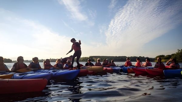 Schüler der Bush Post Primary School beim gemeinsamen Rafting auf einem Gewässer unter bewölktem Himmel.