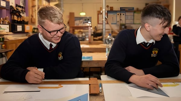 Zwei Schüler der Cabinteely Community School sitzen gemeinsam an einem Tisch und konzentrieren sich auf ihre Arbeit.