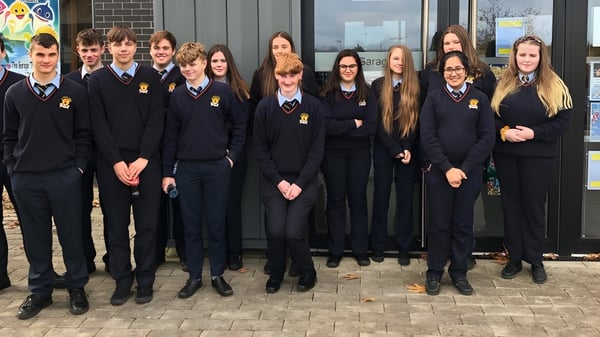 Eine Gruppe von Schülerinnen und Schülern der Cabinteely Community School steht vor einem Backsteingebäude.