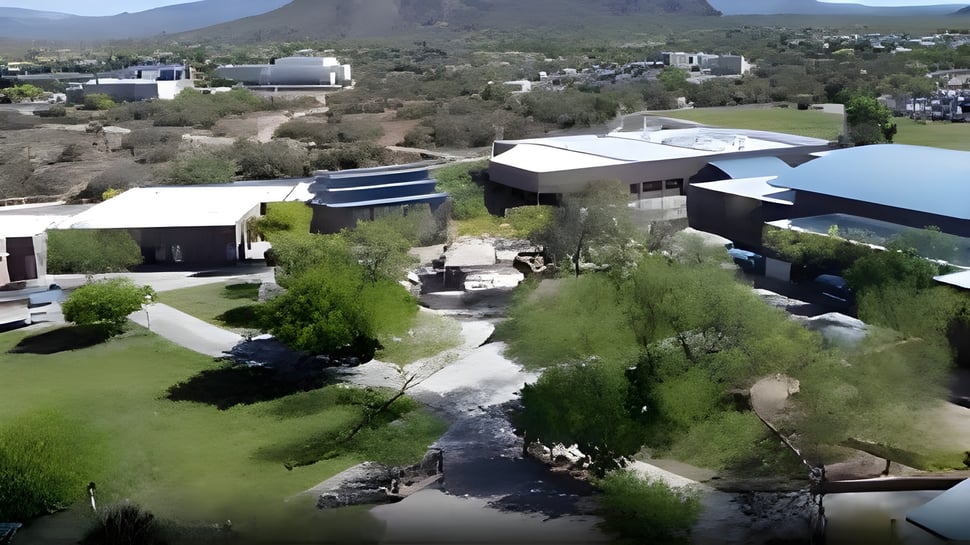 Grüne Landschaft mit Bach und Gebäuden vor Bergen auf dem Campus der Cactus Shadows High School.
