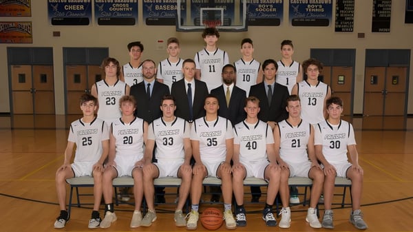 Die Basketballmannschaft der Cactus Shadows High School posiert gemeinsam mit Trainern in der Sporthalle.