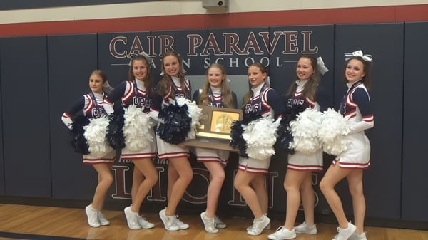 Eine Gruppe Schülerinnen und Schüler der Cair Paravel Latin School steht in einheitlichen Uniformen vor einem Schulbanner.