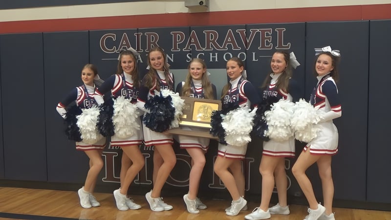 Eine Gruppe Schülerinnen und Schüler der Cair Paravel Latin School steht in einheitlichen Uniformen vor einem Schulbanner.