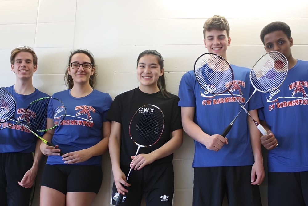 Eine Gruppe von Schülerinnen und Schülern der Cairine Wilson Secondary School posiert mit Tennisschlaegern in einer Sporthalle.