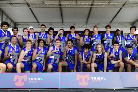 Eine Sportmannschaft der Cairns State High School posiert gemeinsam vor einem Tribal Sport Banner.