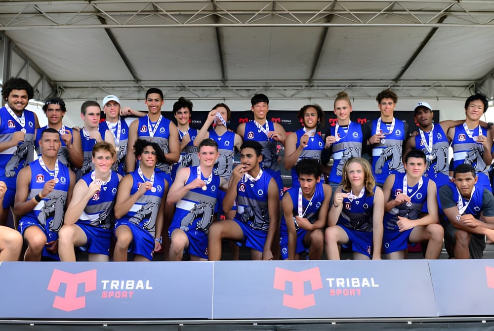 Eine Sportmannschaft der Cairns State High School posiert gemeinsam vor einem Tribal Sport Banner.