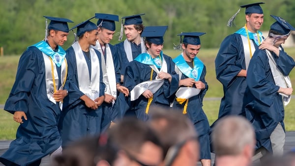 Eine Gruppe von Absolventen in blauen und weißen Talaren steht auf dem Gelände der Cairns State High School zusammen.