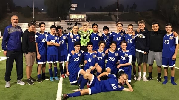 Eine Gruppe von Schülern der Calabasas High School posiert nachts gemeinsam auf einem Fußballfeld mit Anzeigetafel und Stadionbeleuchtung.