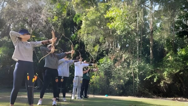Schüler des Calamvale Community College üben Bogenschießen im Freien inmitten grüner Umgebung.