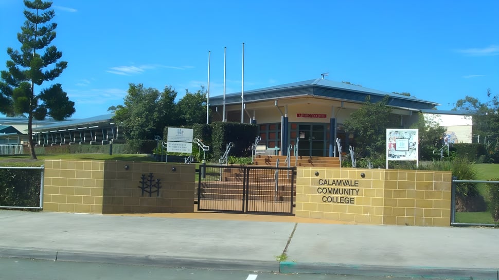 Das Backsteingebäude mit dem Schild Calamvale Community College steht vor Bäumen und einer Grünfläche.