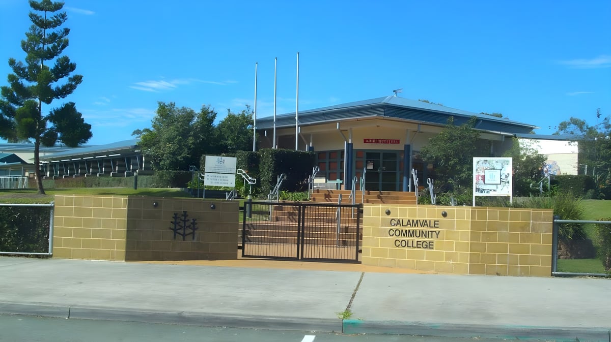 Das Backsteingebäude mit dem Schild Calamvale Community College steht vor Bäumen und einer Grünfläche.