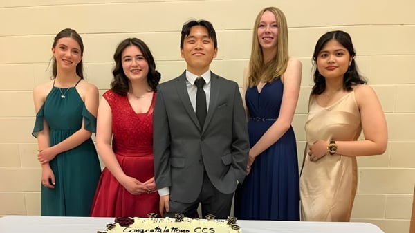 Eine Gruppe von fünf Personen in formeller Kleidung auf dem Campus der Calgary Christian School posiert vor einer Wand.