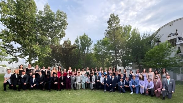 Eine große Gruppe Schülerinnen und Schüler der Calgary Christian School versammelt sich im Freien vor einem Gebäude mit Bäumen im Hintergrund.