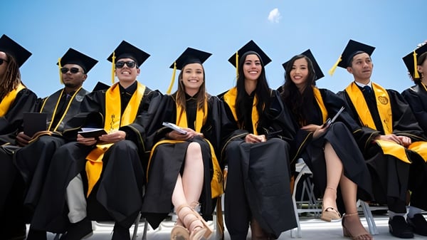 Absolventinnen und Absolventen der California State University Long Beach stehen in Abschlusskleidung zusammen und feiern ihren Erfolg unter blauem Himmel.