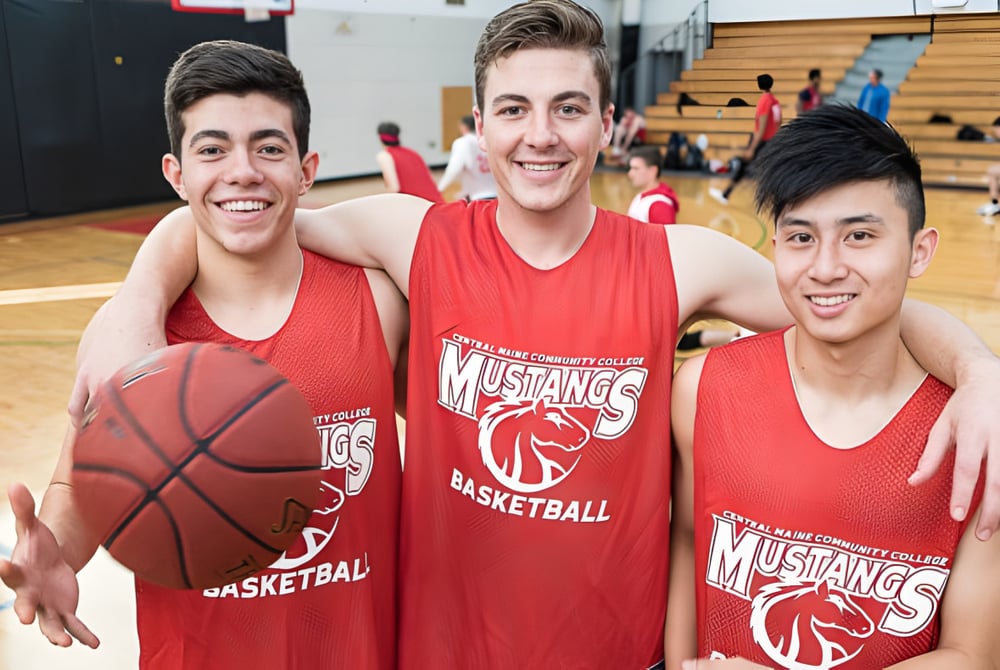 Drei Schüler des Caloundra Christian College in roten Basketballtrikots posieren mit einem Basketball in der Sporthalle.