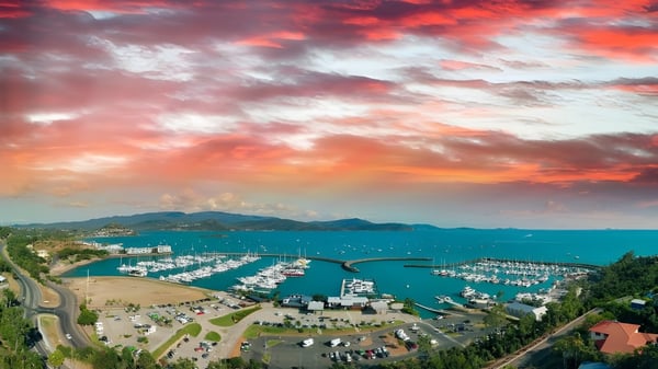 Luftaufnahme eines Küstenhafens mit Bergen im Hintergrund bei Sonnenuntergang in der Nähe des Caloundra Christian College.