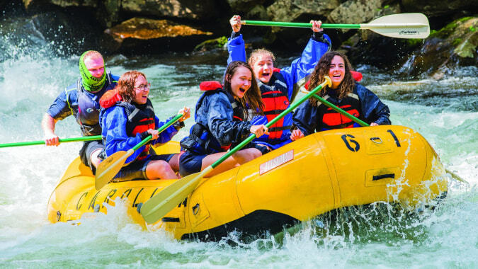 Schüler der Caloundra State High School beim Rafting auf einem Fluss inmitten grüner Landschaft.