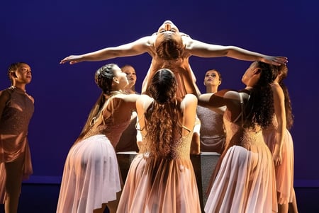 Eine Gruppe von Tänzerinnen in hellen Kleidern führt auf der Bühne der Calvary Christian Academy auf.