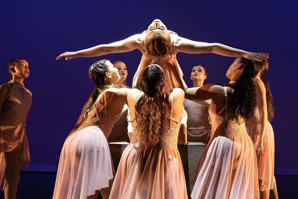 Eine Gruppe von Tänzerinnen in hellen Kleidern führt auf der Bühne der Calvary Christian Academy auf.