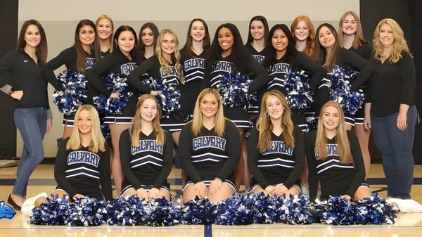 Eine Gruppe von Cheerleaderinnen der Calvary Day School posiert in einheitlichen Uniformen vor neutralem Hintergrund.