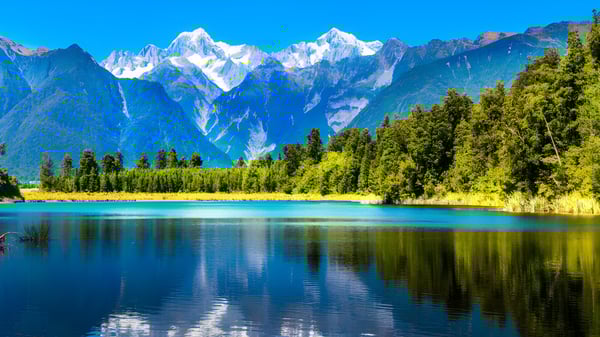 Ein alpiner See mit schneebedeckten Bergen und dichten Wäldern spiegelt die natürliche Landschaft nahe der Cambridge High School wider.