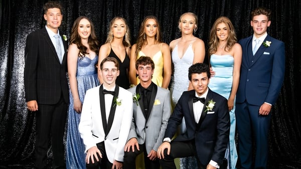 Eine Gruppe von Personen posiert bei einer formellen Veranstaltung vor einem schwarzen Hintergrund auf der Cambridge High School.